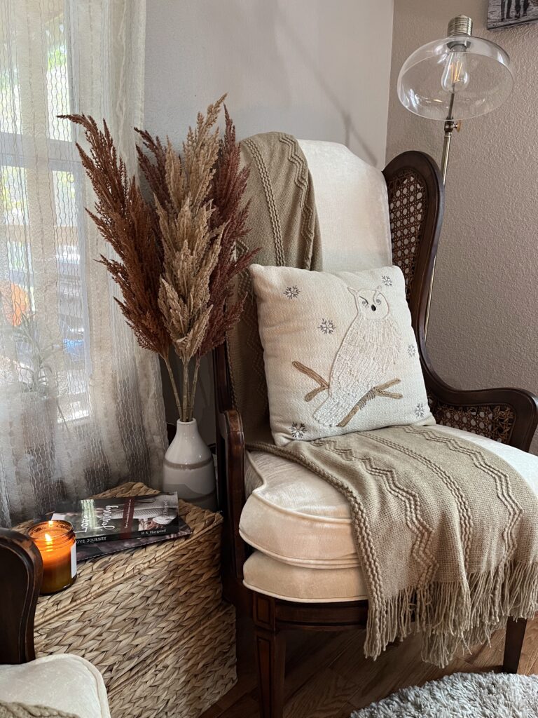 Neutral cozy reading chair with soft blanket, pillow, candle and books