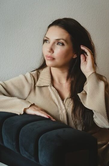 Woman sitting on couch brushing hair from her face-peaceful moment of self-reflection and softness